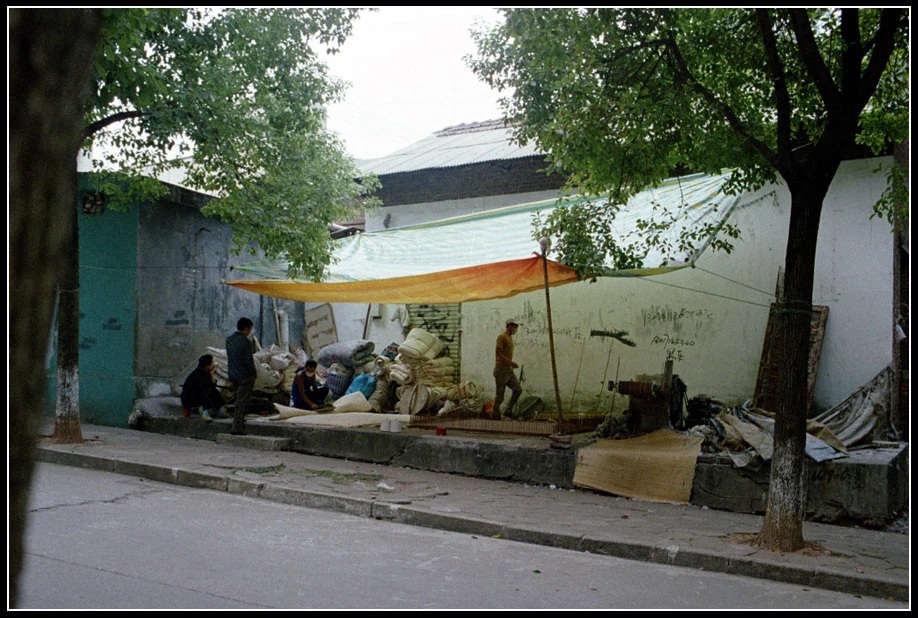 A Family Ginning Cotton A family seated outside their home, engaged in the traditional process of ginning cotton.