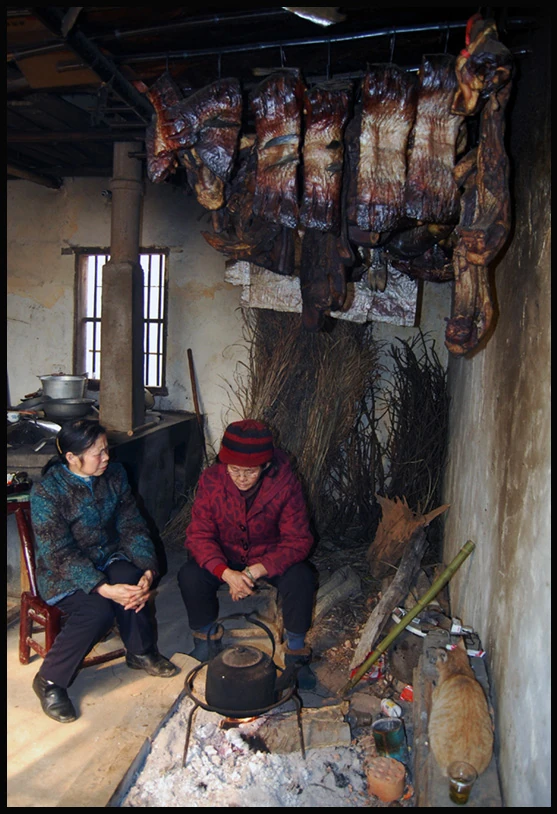 A family gathered in a rustic kitchen preparing traditional dishes for Chinese New Year.