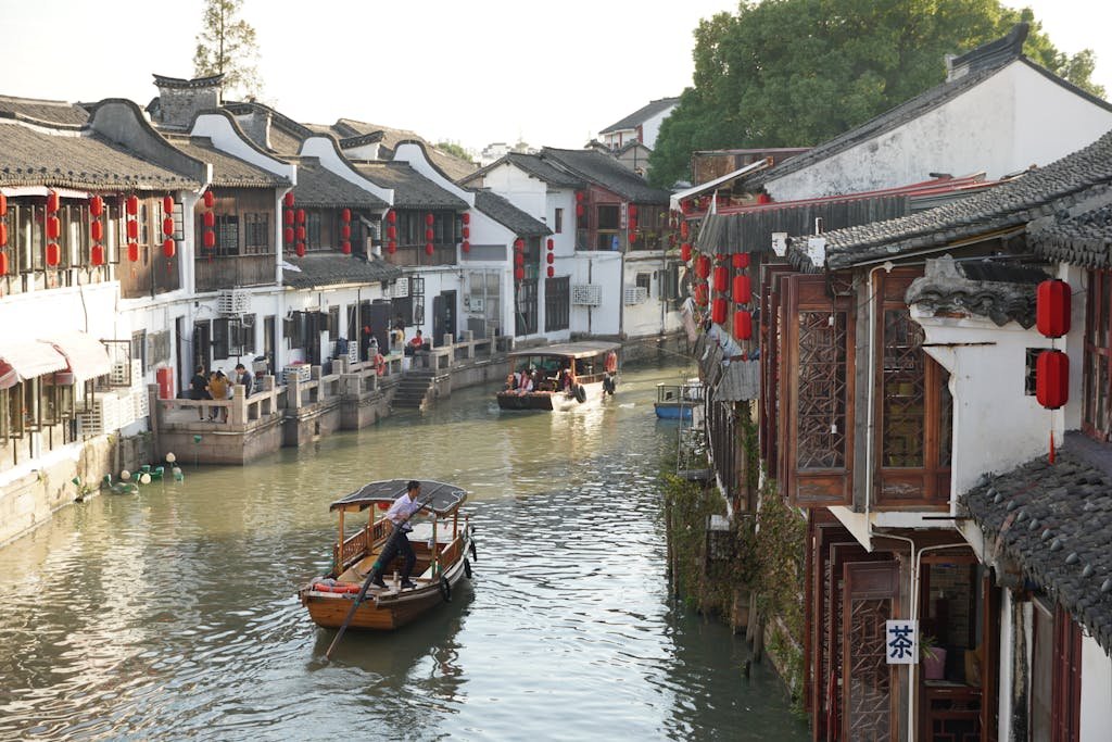 Serene canal view in an ancient Chinese town with boats and traditional architecture.